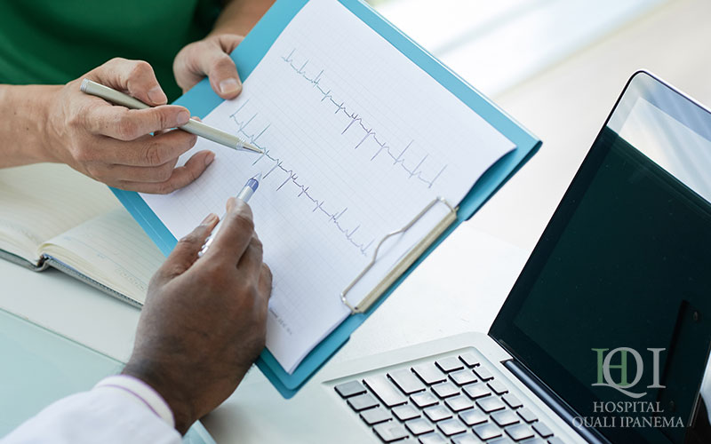 Médico analisando exame de eletrocardiograma em prancheta durante consulta de avaliação cardíaca